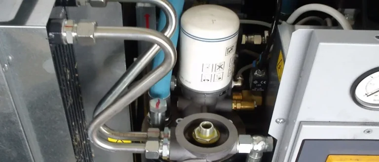Interior of a screw compressor showing air-oil separator, oil filter, and compressor components for maintenance.